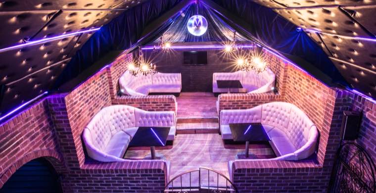 Brick booths with curved seating under fairy lights and a disco ball